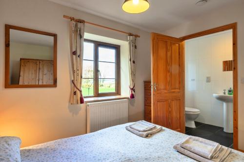 a bedroom with a bed and a toilet and a window at Finest Retreats - Tarkas Holt Log Cabin, Stowford in Little Torrington