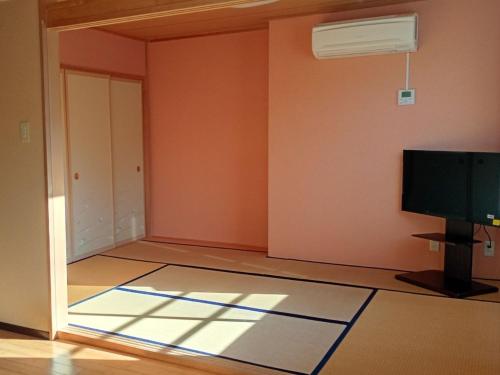 een lege kamer met een flatscreen-tv en een kamer met een deur bij 坂聖 那須塩原 in Nasushiobara