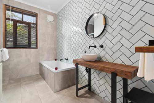 a bathroom with a sink and a mirror and a tub at Hepbirds in Hepburn Springs