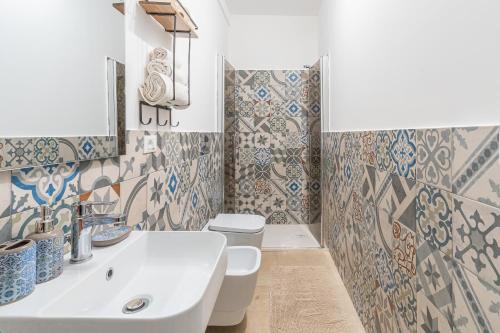 bagno con lavandino, servizi igienici e piastrelle. di I Due Mori Marzamemi a Marzamemi