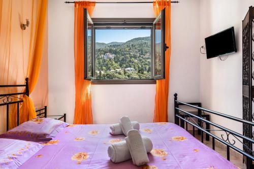 Una cama con un osito de peluche delante de una ventana en Alkionides Apartment 2, en Agios Nikitas