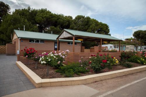 a building with a bunch of flowers in a garden at Moonta Bay Holiday Park in Port Moonta