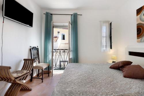 1 dormitorio con 1 cama, TV y balcón en Mdc - Muralhas da Cidade, en Lagos