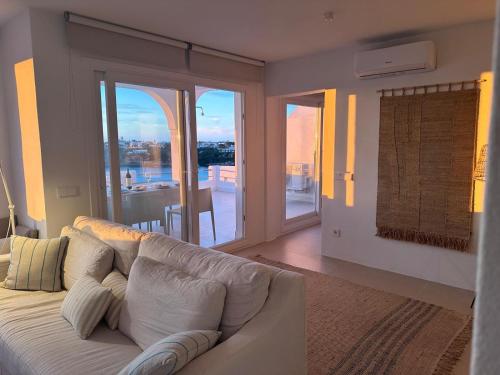 a living room with a white couch and a balcony at Apartamento Poblado marinero in Arenal d'en Castell