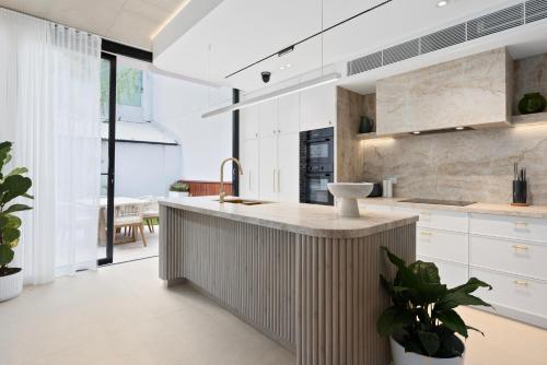 a kitchen with white cabinets and a sink at City-View Retreat with Tranquil Rooftop Spa in Sydney