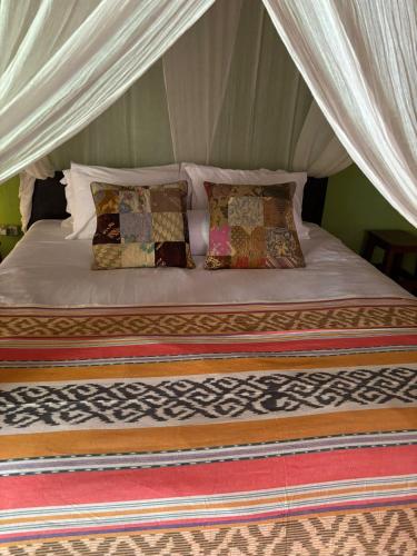 a bed in a tent with pillows on it at Utopia Bungalows Gili Air in Gili Islands