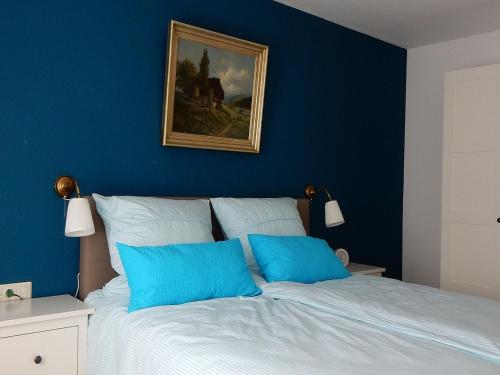 a bedroom with blue walls and a bed with blue pillows at Ferienwohnung am Wildpflanzenpark in Unterkirnach