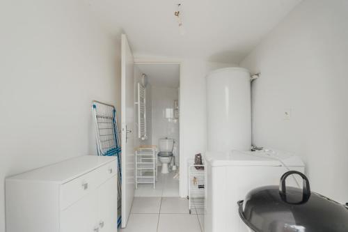 a white kitchen with a sink and a refrigerator at Ancien moulin à vent du 19e siècle in Cherrueix