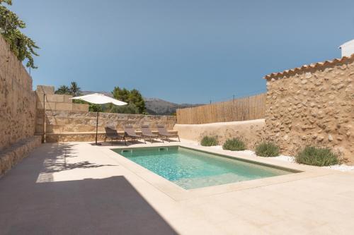 a swimming pool with chairs and a stone wall at Cas Suis 9 in Campanet