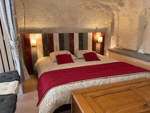 a bedroom with a large bed with red pillows at Troglo - gîte dans la pierre in Villaines-les-Rochers