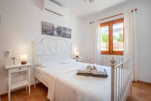 a white bedroom with a white bed and a window at Villa Balena with heated pool in Sa Ràpita