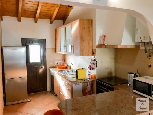 une cuisine avec un réfrigérateur en acier inoxydable et des armoires en bois dans l'établissement Casas Da Lagoa - T2 Sul, à Aldeia de Brescos