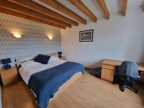 Un dormitorio con una cama, un escritorio y una silla. en La Grande Maison de Janaillat, en Janaillat