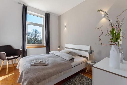 a white bedroom with a bed and a window at Werkgut - Charmantes Loft in Meezen