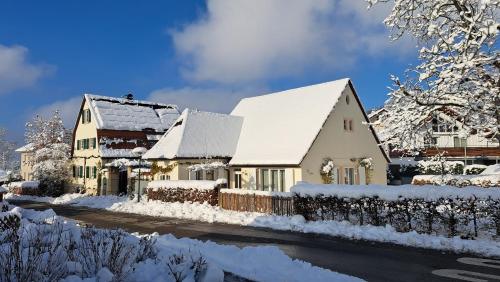 une maison recouverte de neige à côté d'une rue dans l'établissement Ferienscheune, à Daisendorf