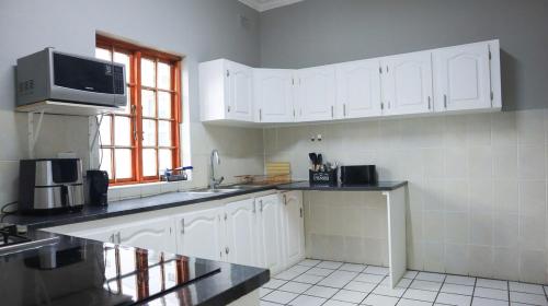 a kitchen with white cabinets and a microwave at Comfy stay in East London