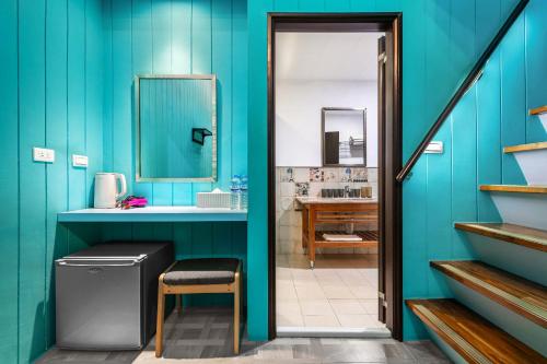 Un baño azul con un cubo de basura y un espejo en Kenting Hemingway, en Kenting