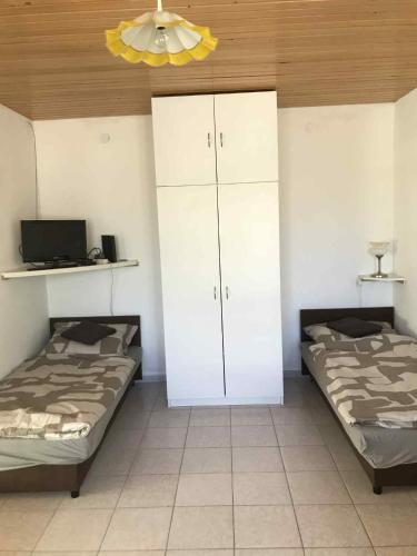 a bedroom with two beds and a white cabinet at Tomi Vendégház in Kóczántanya