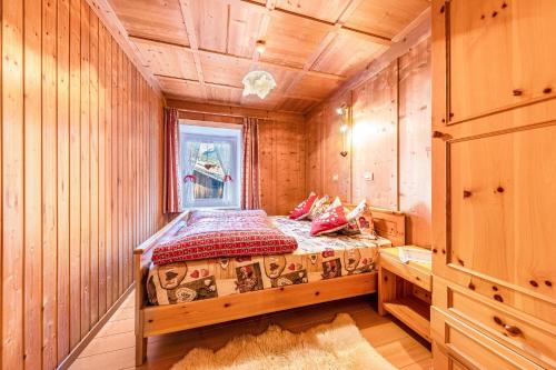een slaapkamer met een bed in een kamer met houten wanden bij Ciasa Tach in Pozza di Fassa