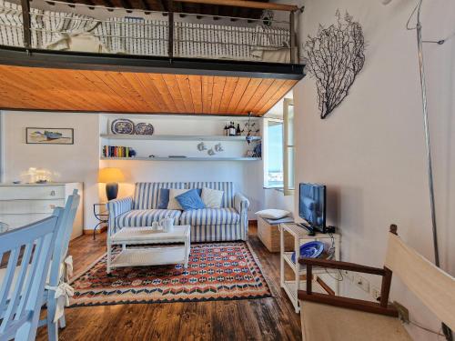 a living room with a couch and a tv at Loft il Mare Rio Marina front sea in Rio Marina