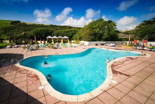 ein großes Schwimmbecken mit Menschen im Wasser in der Unterkunft Holiday Home with Hot Tub Cornish Country SeaSide in Newquay Bay Resort