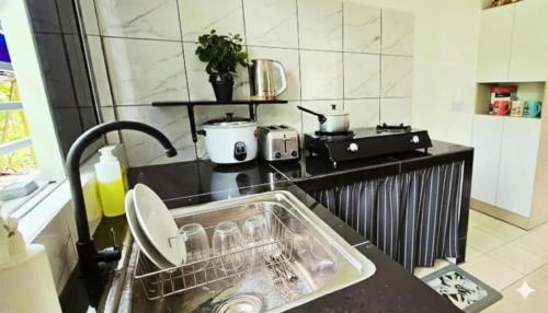 une cuisine avec un égouttoir dans un évier dans l'établissement Feel Borneo Cozy Homestay in Penampang, à Penampang