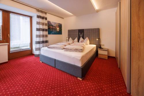 - une chambre avec un lit et un tapis rouge dans l'établissement Gästehaus Wolfgang Königsee -8-, à Ruhpolding