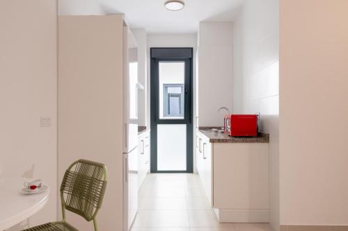 a kitchen with white cabinets and a chair in it at Iberos Home in Seville