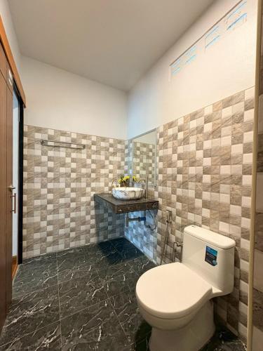 a bathroom with a toilet and a tiled wall at Baan I Ta Lay Koh Yao Noi in Ko Yao Noi