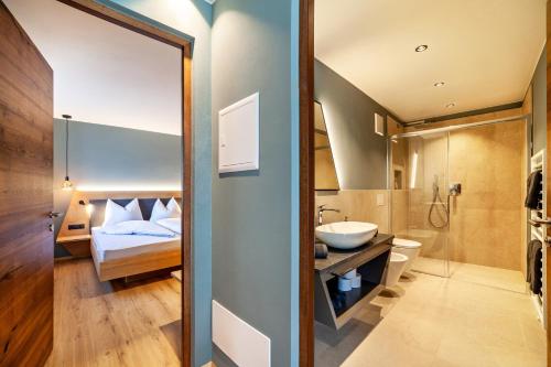 サルトゥジオにあるAktiv Lodge Meran - Terrace Oneのベッドと洗面台と鏡のあるバスルーム