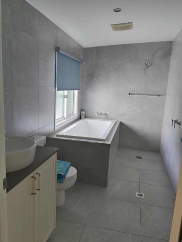 a bathroom with a tub and a toilet and a sink at Carefree Comfort in Deception Bay