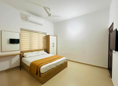 a bedroom with a bed and a flat screen tv at Easy Nest Residency in Kannur