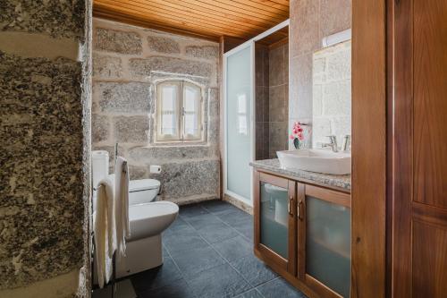a bathroom with a white toilet and a sink at Cantinho da Tilde in Fafe
