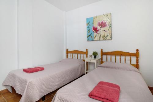 two beds in a room with white walls and red towels at Apartamento Callao, La Graciosa in Caleta de Sebo