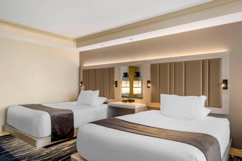 a hotel room with two beds with white sheets at Wyvern Hotel, an Ascend Collection Hotel in Punta Gorda
