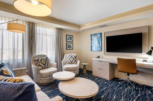 a living room with a tv and a couch and chairs at Wyvern Hotel, an Ascend Collection Hotel in Punta Gorda