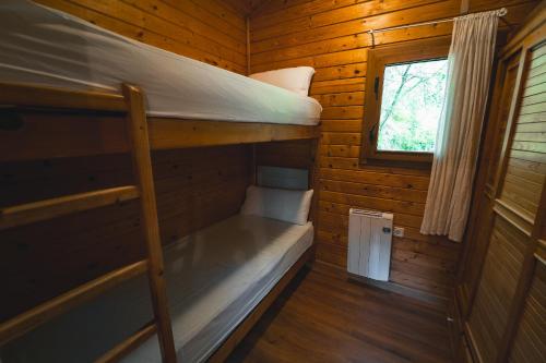 HolaCamp Vall Natura في Sant Miquel de Campmajor: غرفة نوم بسريرين بطابقين في كابينة خشبية