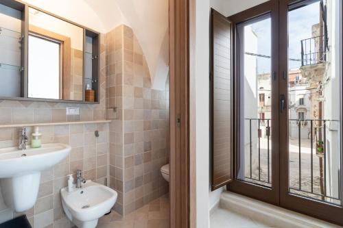 a bathroom with a sink and a toilet and a window at La Greca 59 in Putignano