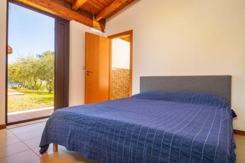 Un dormitorio con una cama azul y una gran ventana. en Tuccios villa, en Solicchiata