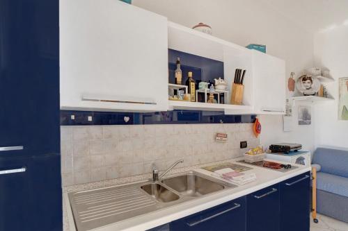 eine Küche mit Spüle und blauen Schränken in der Unterkunft Casa vacanze Leslie in Albenga
