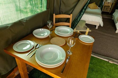 ein Holztisch mit Tellern und Weingläsern darauf in der Unterkunft Safari Glamping Portugal Gazelle in Ventosa