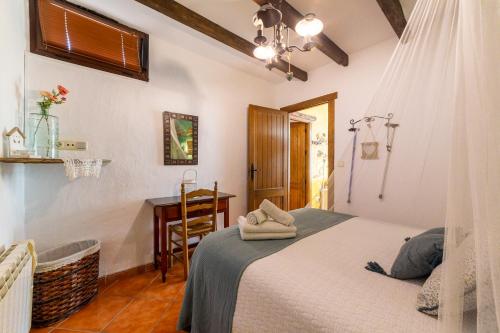 a bedroom with a bed and a table and a desk at La Casa Al Revés in Laroya