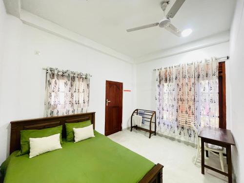 a bedroom with a green bed and a window at Lakru Home Stay in Weligama