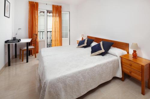 een slaapkamer met een wit bed, een bureau en een tafel bij Meraki Nerja in Nerja