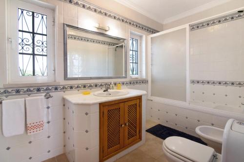 a bathroom with a sink and a toilet and a mirror at Casa dos Avós in Albufeira