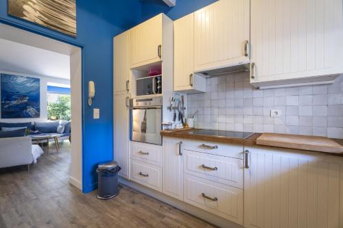 una cucina con armadi bianchi e parete blu di Villa Baliba a Hyères