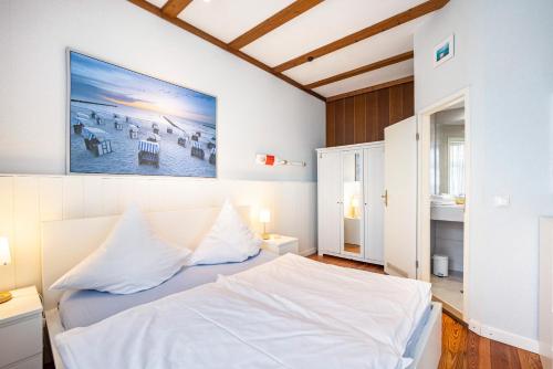 a white bedroom with a bed and a painting on the wall at Ferienwohnungen Fehlingstr 28 in Travemünde