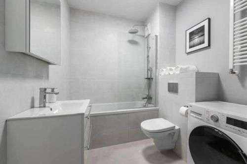 Un baño blanco con inodoro y lavadora. en Exclusive Apartments on Kasprzaka Street - Warsaw Wola, en Varsovia