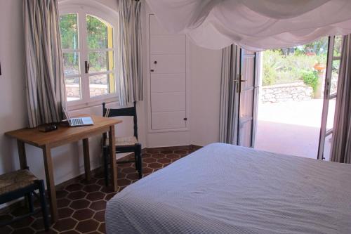 a bedroom with a bed and a desk and a window at Villa Le Ginestre di mare in Capoliveri