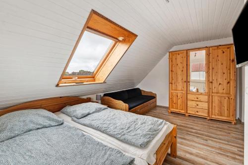 Un dormitorio con una cama y una ventana y una silla. en Kleiner Leuchtturm-Backbord, en Fehmarn